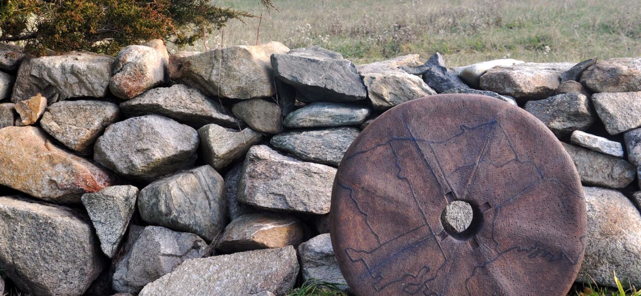 Ashwini Bhat’s Millstone I, 2015, in front of the stonewall rebuilt by Dr. Robert French by the Slocum river, Westport, Massachusetts. Stoneware, 26 in. diameter. Photo by author.