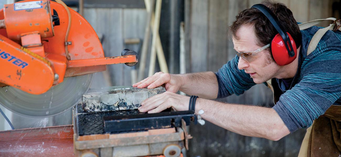 Mess slices a fired sculpture from his Reclaim series on a diamond wet saw outside his home studio. Photograph by Erin Little, May 2015.
